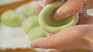 將均分的艾草面團(tuán)搓成圓，挖一個(gè)窩，放入餡心，再搓成圓。