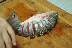 將鱸魚清洗干凈，從脊椎處切斷至腹部，腹部保留1cm左右不要切斷。