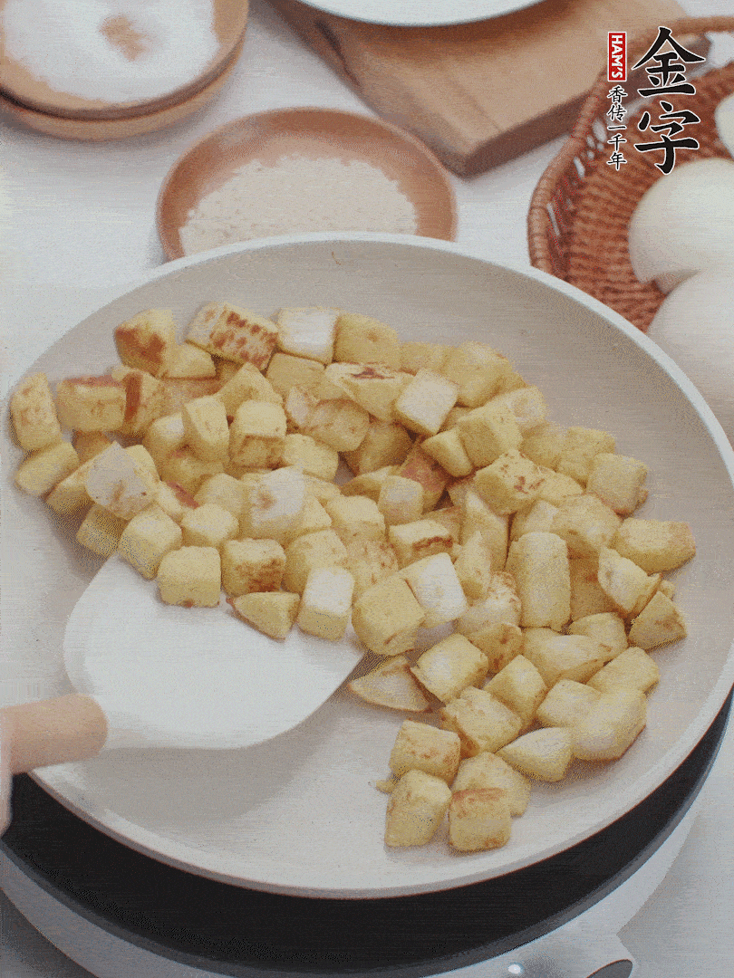 起鍋熱油，倒入饅頭丁，小火煎至蛋液凝固定型再翻面，饅頭丁部煎至金黃時盛起待用。