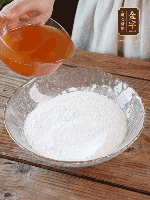 轉(zhuǎn)化糖漿、枧水、花生油攪拌均勻，加入面粉混合，醒發(fā)2小時(shí)。捏成23g一個(gè)的小球